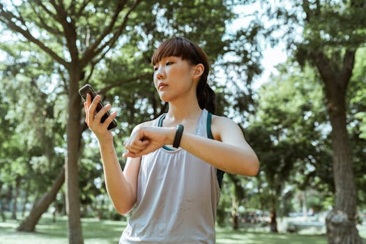 pexels-photo-4426517-4426517 Young Asian woman checking her fitness tracker on a sunny day in the park, staying active and healthy.